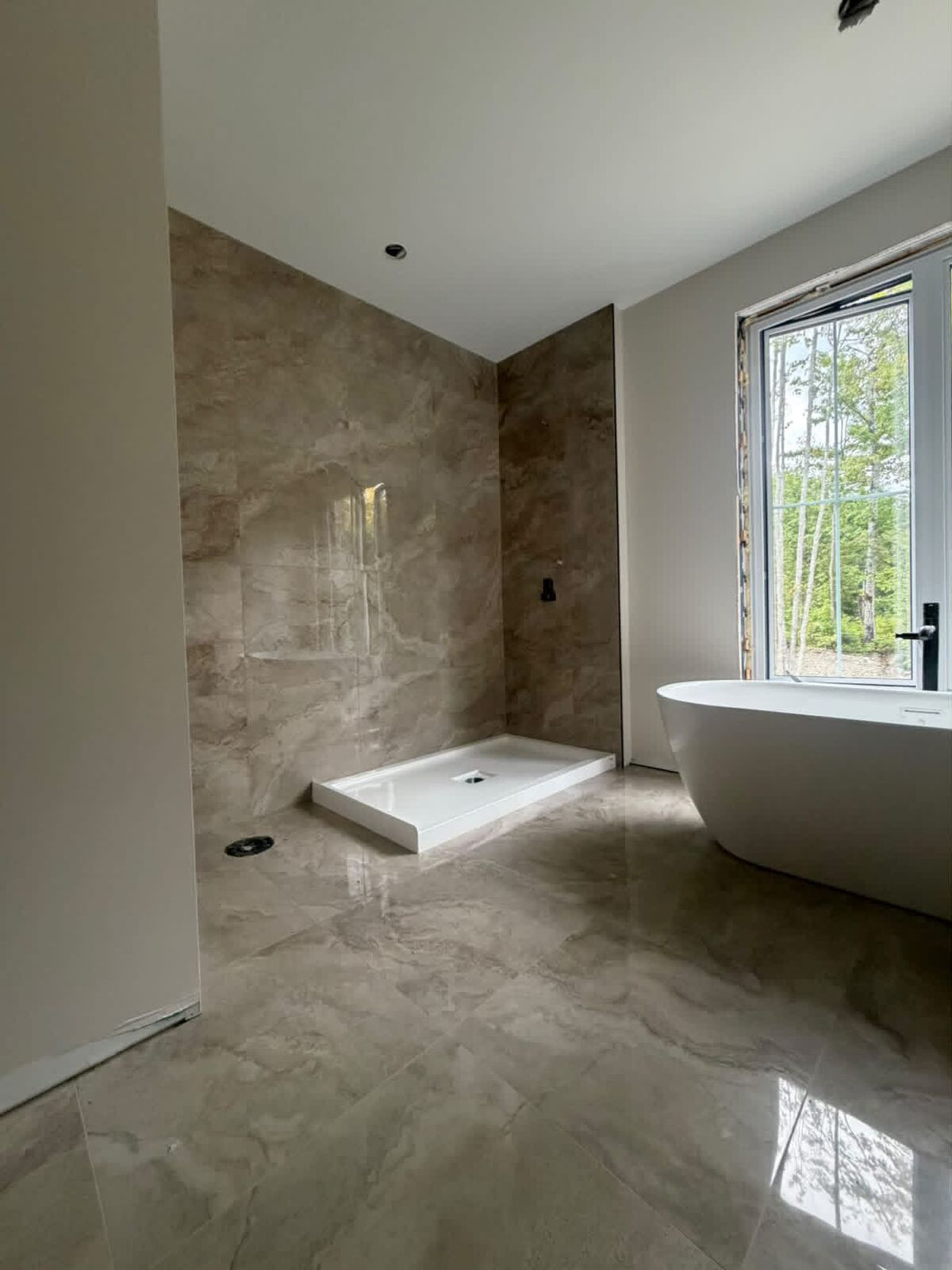Plancher grand format effet marbre beige poli posé par SD Surfaces, avec baignoire autoportante