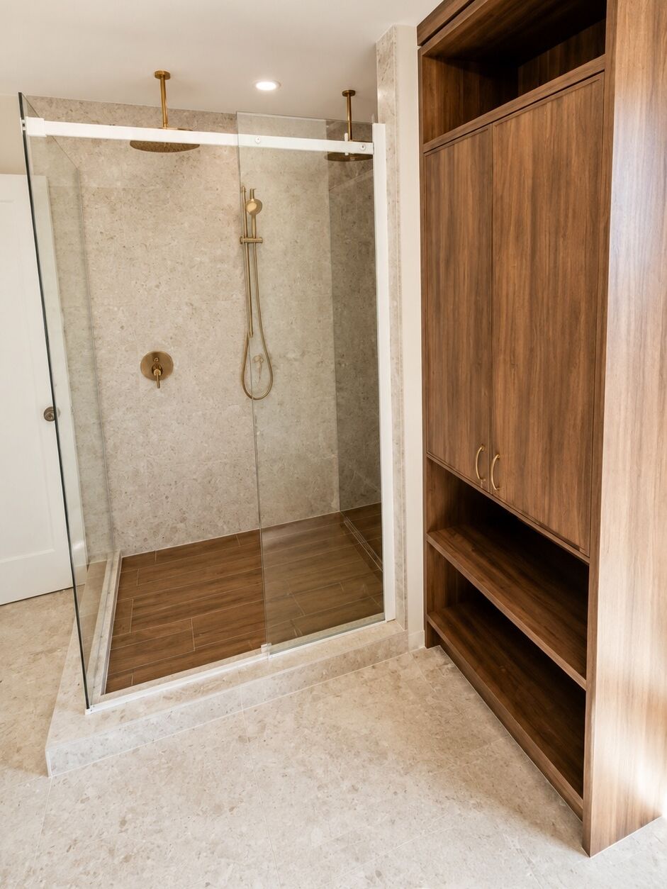 Douche vitrée en céramique effet terrazzo, plancher effet bois et meuble en noyer
